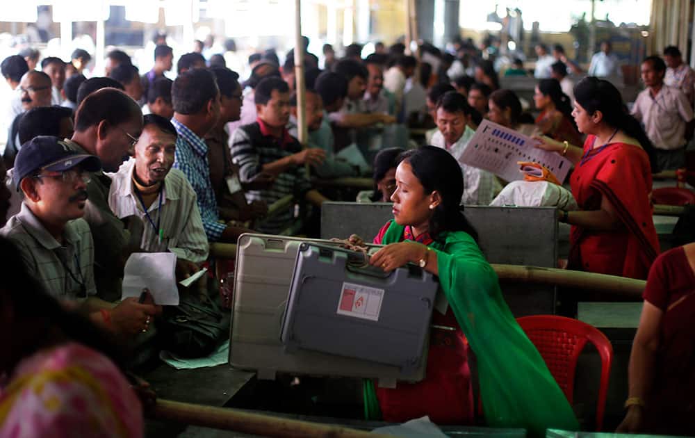 Election officials, left, receive electronic voting machines and other election material at a distribution center set up at a school campus beforeheading to their respective polling stations on the eve of the first phase of national elections in Dibrugarh, in the northeastern Indian state of Assam.
