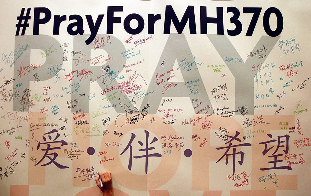 A man writes messages for passengers aboard the missing Malaysia Airlines Flight MH370 before a mass prayer for them, in Kuala Lumpur, Malaysia.