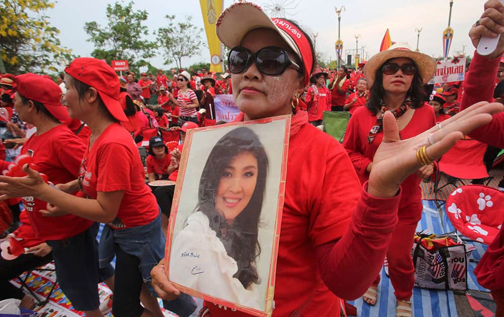 A pro-government Red Shirt member dances with a portrait of Thai Prime Minister Yingluck Shinawatra during a rally in Bangkok.
