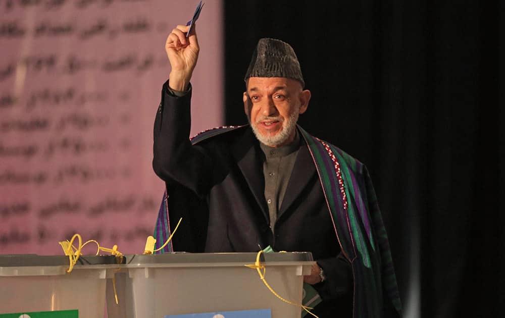 Afghan President Hamid Karzai, shows his ballot paper to the media before he casts his vote at Amani high school, near presidential palace in Kabul, Afghanistan.
