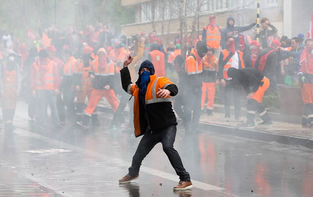 A protestor hurls a rock toward police officers during a trade union demonstration in the European Quarter of Brussels.