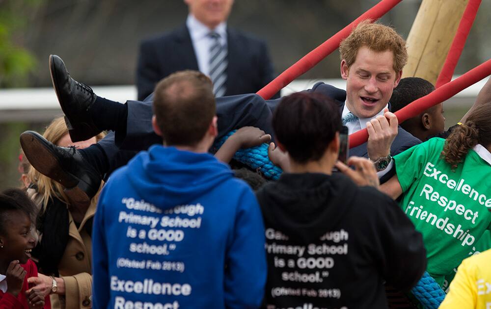 Britain`s Prince Harry is pushed on a swing by children from Gainsborough Primary School as he visits the redeveloped Queen Elizabeth Olympic Park in London.