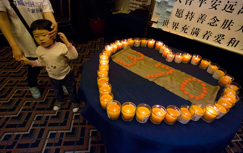 Relatives of Chinese passengers onboard the Malaysia Airlines plane, Flight MH370 stand near candles formed around another candles that form up 370 at a prayer room in Beijing, China.