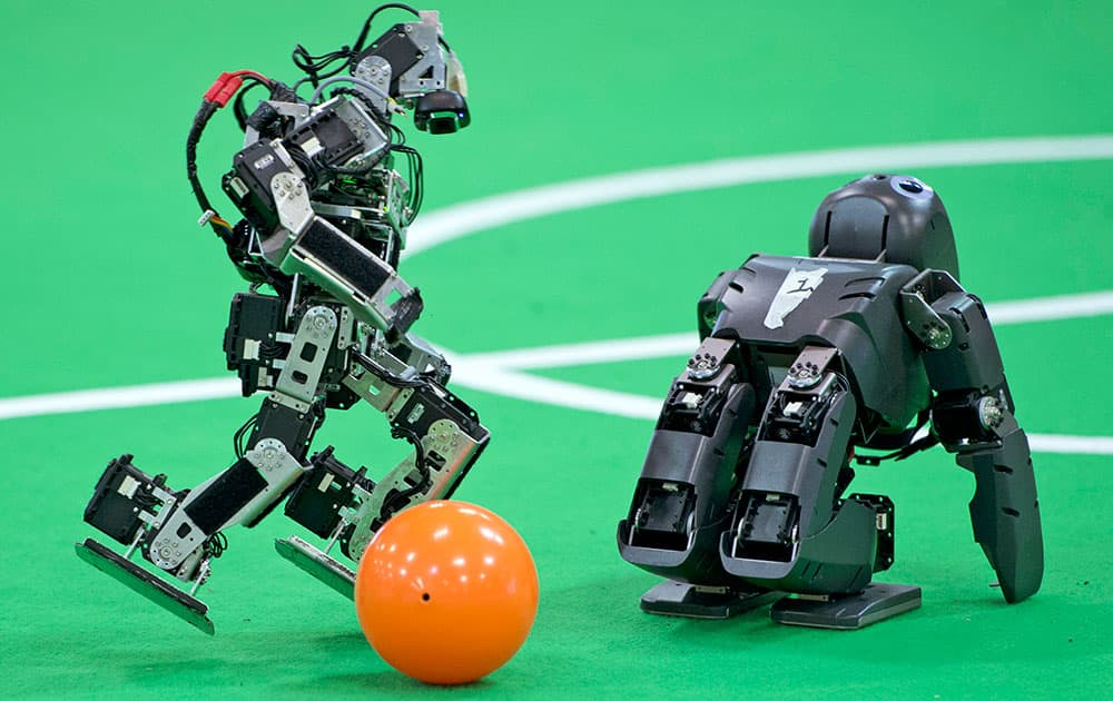 A robot of a German team, left, plays the ball besides a British team robot in the Kids League at the RoboCup German Open 2014 in Magdeburg, Germany.