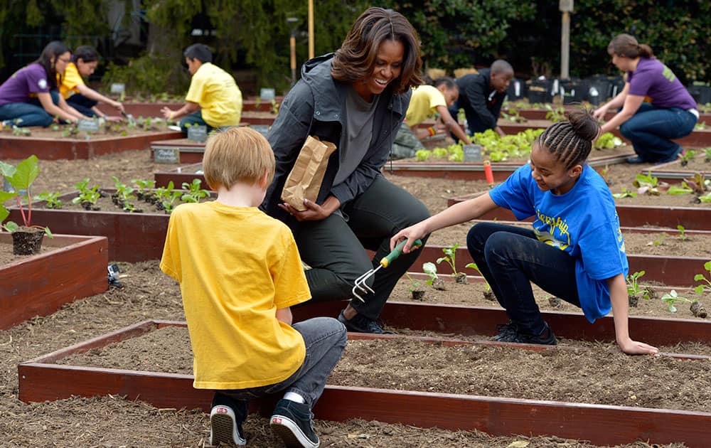 First lady Michelle Obama talks with Friendship Public Charter Elementary School student Dynasty Meade, center, and Bancroft Elementary School student Silas Stutz, left, as they plant Lincoln oats in the White House Kitchen Garden at the White House in Washington.