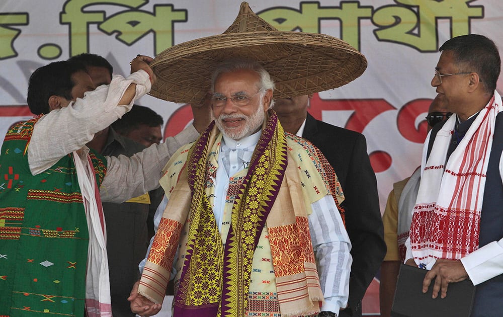 Narendra Modi is presented with a traditional hat during an election campaign rally at Gogamukh, Assam.