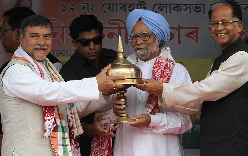 Prime Minister Manmohan Singh receives a traditional memento from Chief Minister of Assam state Tarun Gogoi and Congress party leader Bhubaneswar Kalita, during an election campaign rally at Khumtai, Assam.