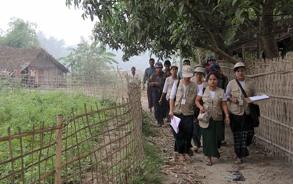 Myanmar police officers walk with census enumerators as they collect information at Bu-May village in Sittwe, Rakhine State, western Myanmar.