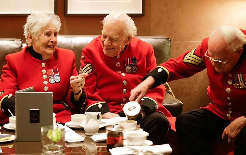 Chelsea Pensioners Audrey Merton, left, Ron Ward, centre, and Frank Treasure, right, react, during afternoon tea, at The Cavendish hotel in London.