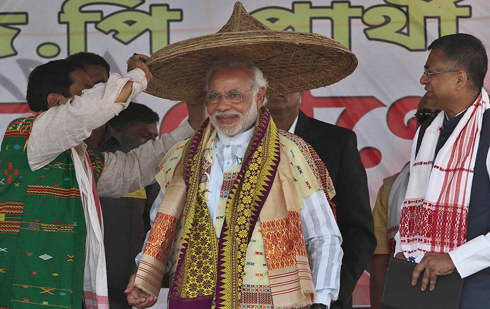 Narendra Modi is presented with a traditional hat during an election campaign rally at Gogamukh, Assam.