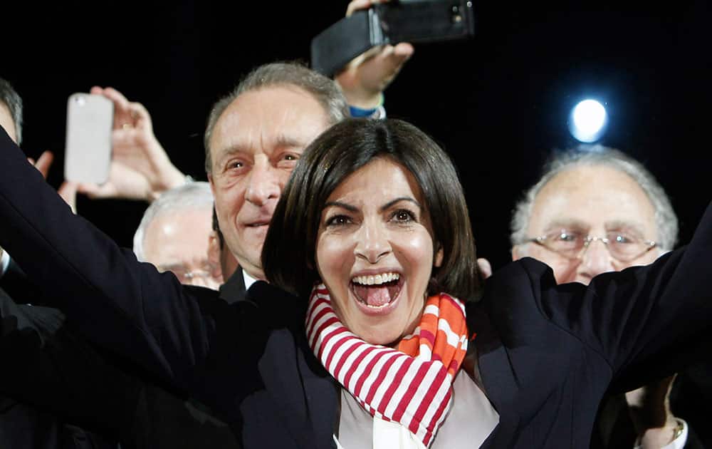 French Socialist Party deputy mayor of Paris, Anne Hidalgo, center, smiles, as outgoing mayor Bertrand Delanoe, stands behind her, during a speech after results were announced in the second round of the French municipal elections, in Paris.