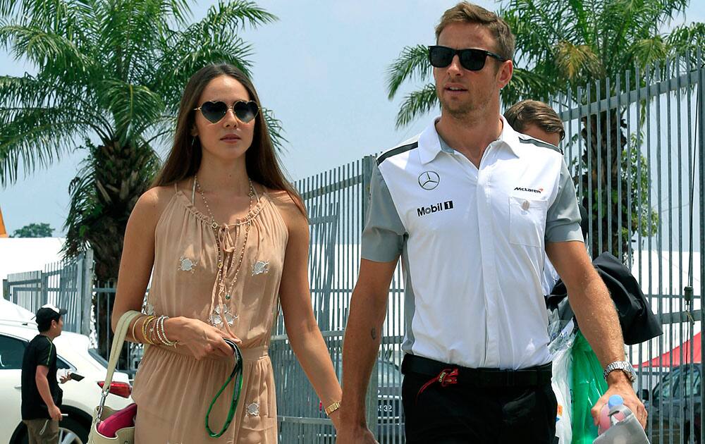 McLaren driver Jenson Button, right, of Britain and his fiancee Jessica Michibata arrive at the paddock for the Malaysian Formula One Grand Prix at Sepang International Circuit in Sepang, Malaysia.