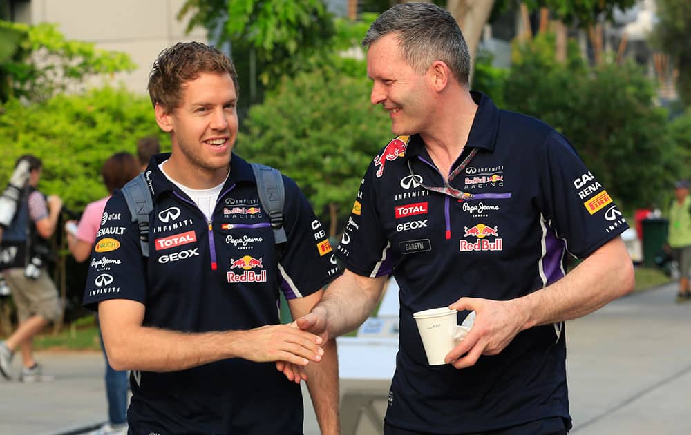 Red Bull driver Sebastian Vettel, left, of Germany is greeted by his crew member as he arrives at the paddock for a practice session ahead of the Malaysian Formula One Grand Prix at Sepang International Circuit in Sepang, Malaysia.
