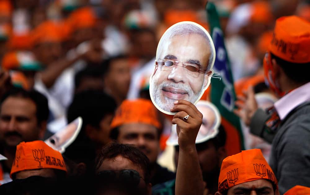 A Bharatiya Janata Party supporter holds high a mask of their prime ministerial candidate Narendra Modi during an election rally at Hiranagar, Jammu.
