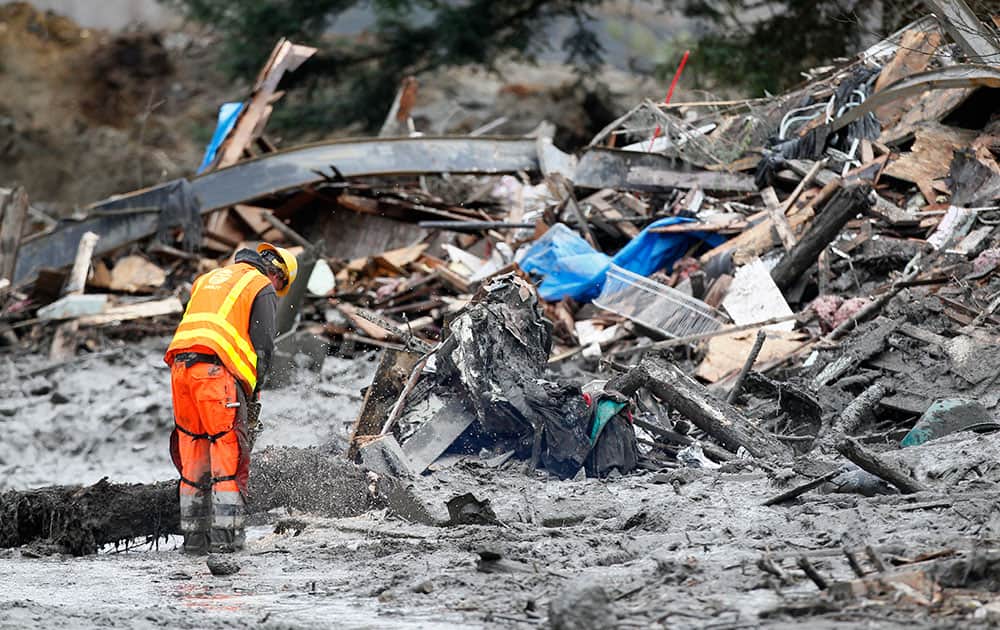 A worker uses a chain saw at the scene of a deadly mudslide that covers the road, in Oso, Wash.