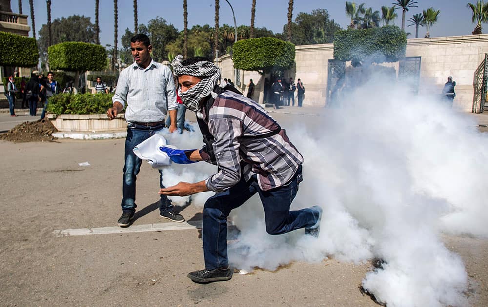 One of the supporters of Egypt`s ousted President Mohammed Morsi picks up a tear gas canister shot by security forces to throw back during their clashes at Cairo University in Giza, Egypt.