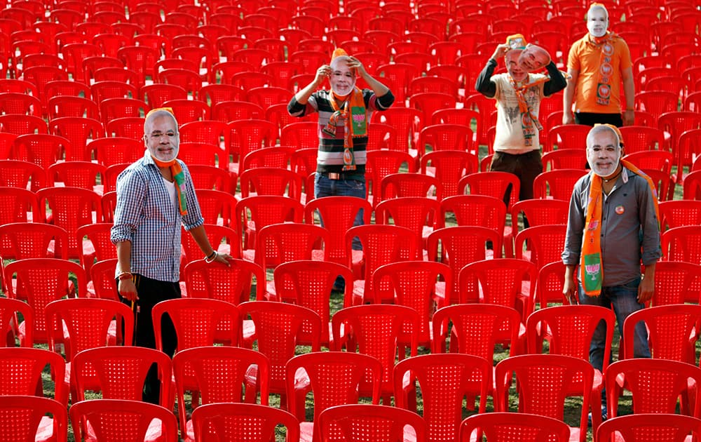 Bharatiya Janata Party supporters wear masks of their prime ministerial candidate Narendra Modi while waiting for the start of an election rally at Hiranagar, a village near Jammu.