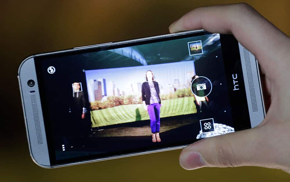 The new HTC One M8 is demonstrated, in New York. HTC is updating its flagship HTC One smartphone by giving it a larger screen, better software and a camera that`s easier to use.