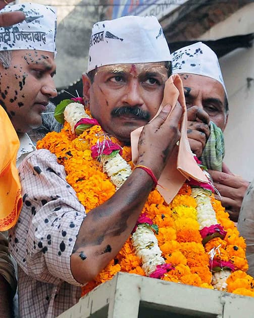 AAP convener Arvind Kejriwal wipes his face after protesters threw black ink on him during a road show in Varanasi.