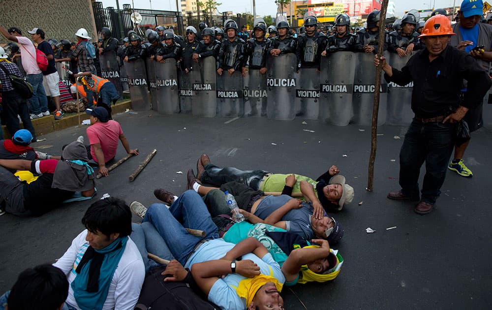 Miners lie on the ground near riot policemen during a protest organized by artisanal and small-scale gold miners in Lima, Peru.