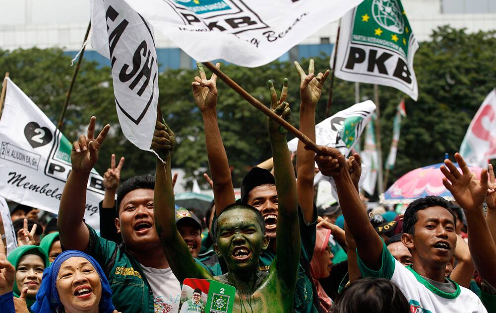 A supporter with his face painted in the color of the National Awakening Party cheers during a campaign rally of the party, led by Indonesian Manpower and Transmigration Minister Muhaimin Iskandar, in Jakarta, Indonesia.