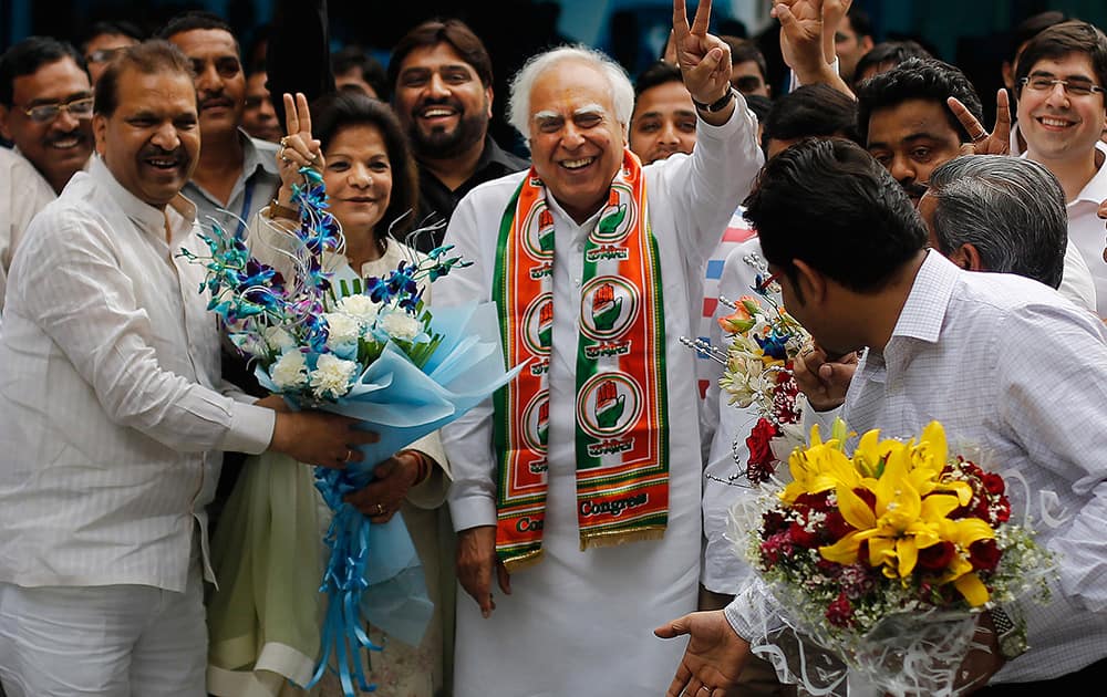 Congress party leader Kapil Sibal and his wife Promila Sibal flash victory signs as supporters present them with flower bouquets after Sibal filed his nomination papers for the upcoming parliamentary elections in New Delhi.
