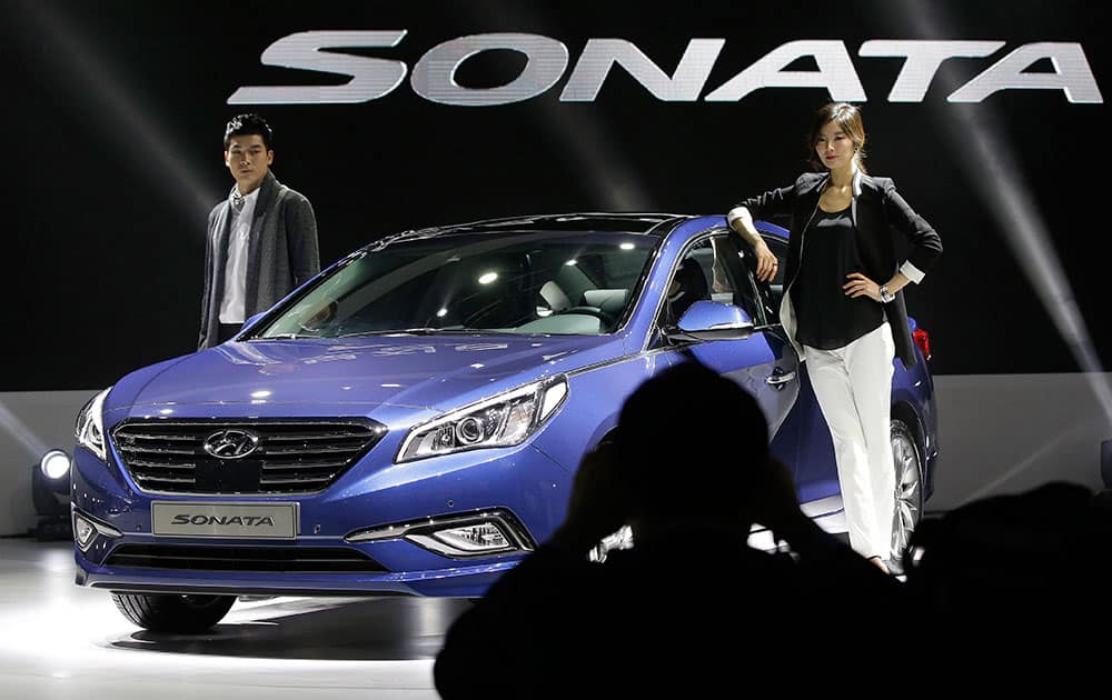 A visitor takes photos as models pose next to Hyundai Motors` all-new Sonata sedan during its unveiling ceremony in Seoul, South Korea. The vehicle is scheduled to go on sale in South Korea later this month.