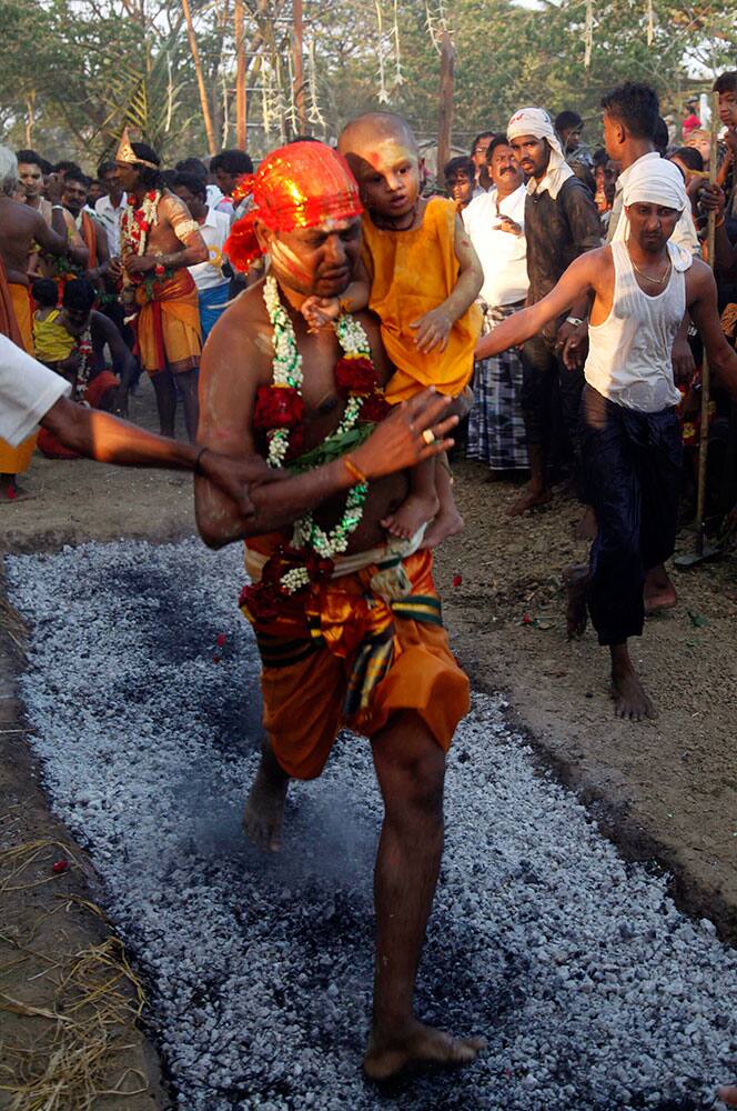 A Hindu devotee carrying a child walk on burning embers in a pit during a traditional Hindu fire festival in Dalla, about 15 kilometers (9 miles) south of Yangon, Myanmar.
