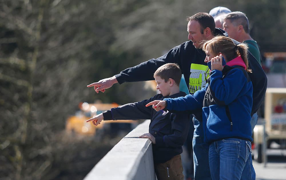 Residents watch as debris comes down the Stillaguamish River from the Whitman Road bridge east of Oso, Wash.