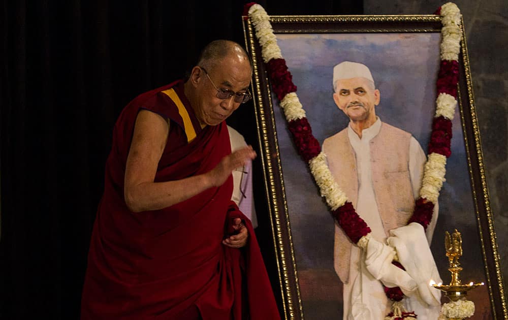 Tibetan spiritual leader the Dalai Lama prepares to return to his chair after paying respects before a painting of India’s former prime minister Lal Bahadur Shastri, before launching a book on Shastri in New Delhi.
