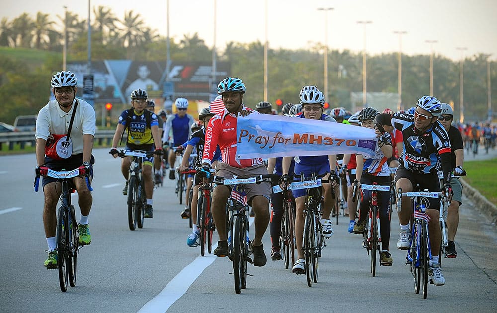 Cyclists hold up a banner reading `Pray for MH370` during