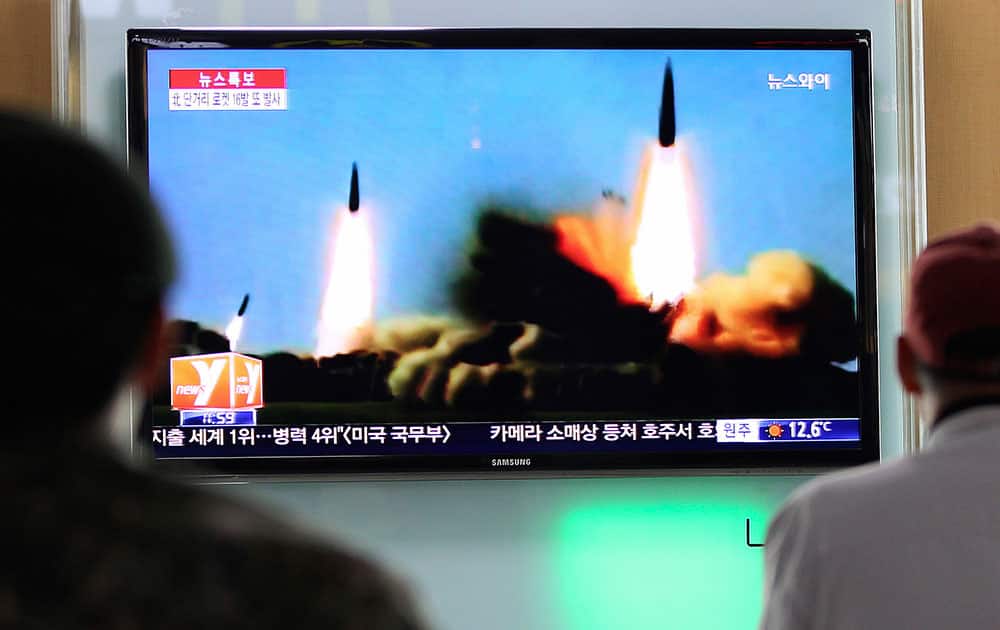 People watch a TV news program showing rockets launched by North Korea, at Seoul Railway Station in Seoul, South Korea.