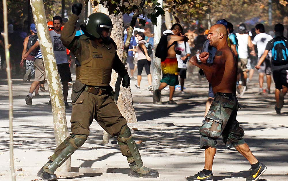 A protester confronts a riot police during violent clashes at the end of a protest march in Forestal Park, in Santiago, Chile.