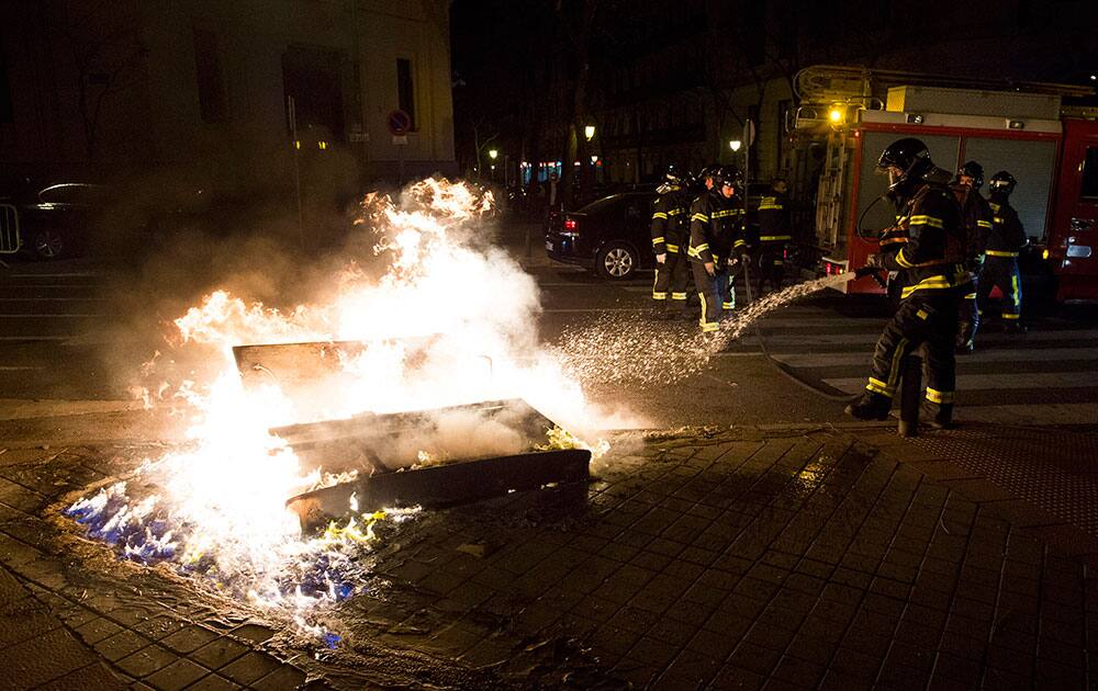 A fireman extinguishes a fire set by demonstrators during a protest against the government in Madrid, Spain.