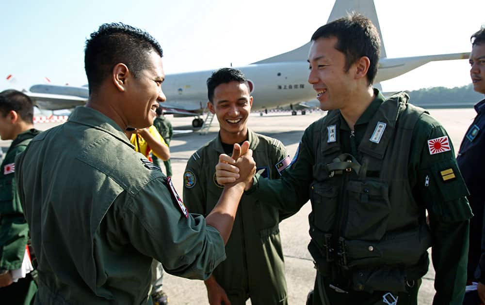 A crew member of Japan`s Maritime Self-Defense Force, right, is wished well by a crew member of the Royal Malaysian Air Force before leaving the Royal Malaysian Air Force base for Australia to join a search and rescue operation for the missing Malaysia Airlines, flight MH370, in Subang, Malaysia.