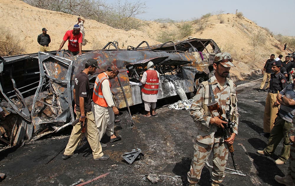 Pakistani rescue workers and policemen check the wreckage of vehicles destroyed in a road accident, near Gadani, Pakistan.