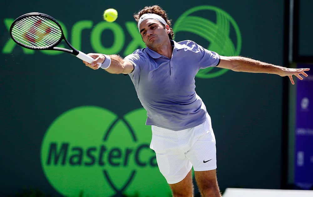 Roger Federer, of Switzerland, reaches for a return against Ivo Karlovic, of Croatia, during a match at the Sony Open tennis tournament.
