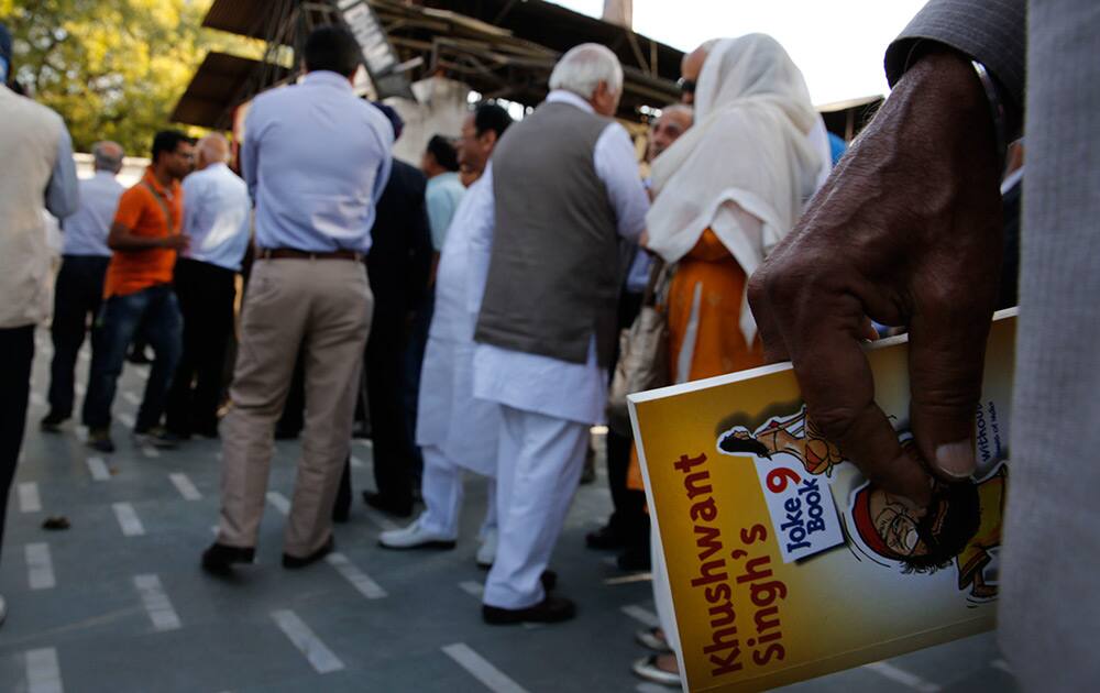 An admirer of Khushwant Singh holds a copy of his famous Joke book as he stands to offers his condolences during Singh`s cremation, in New Delhi.