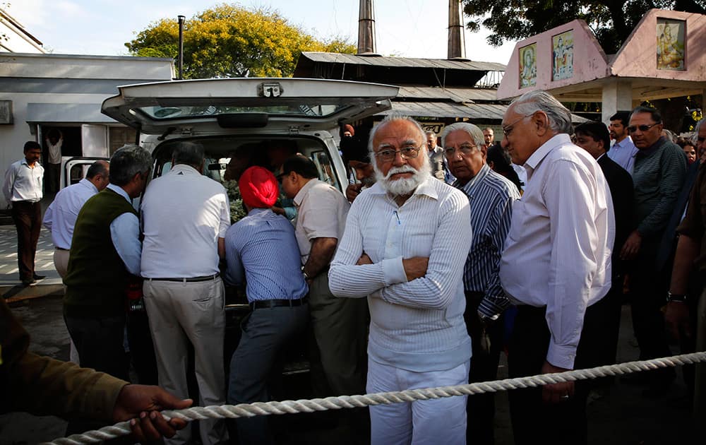 Rahul Singh, son of Khushwant Singh, center in white, stands as relatives and friends take out the body of his father from a mortuary van for cremation, in New Delhi.