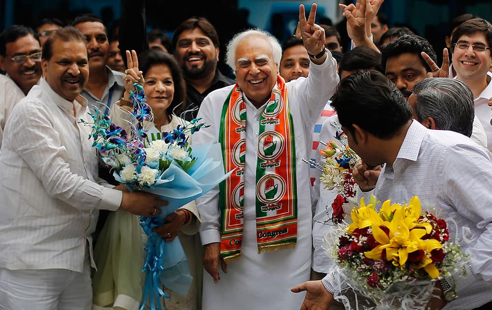 Congress party leader Kapil Sibal and his wife Promila Sibal flash victory signs as supporters present them with flower bouquets after Sibal filed his nomination papers for the upcoming parliamentary elections in New Delhi.