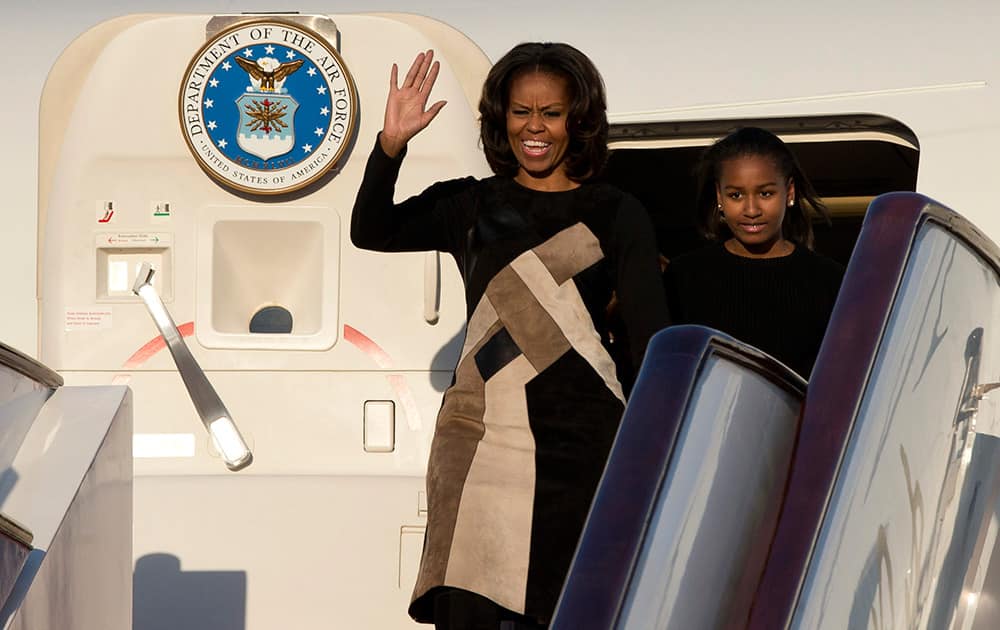 US First Lady Michelle Obama gestures as she and her daughter Sasha leave their plane at Capital International Airport in Beijing. Michelle Obama has arrived in Beijing with her mother and daughters to kick off a seven-day, three-city tour where she will focus on education and cultural exchange.