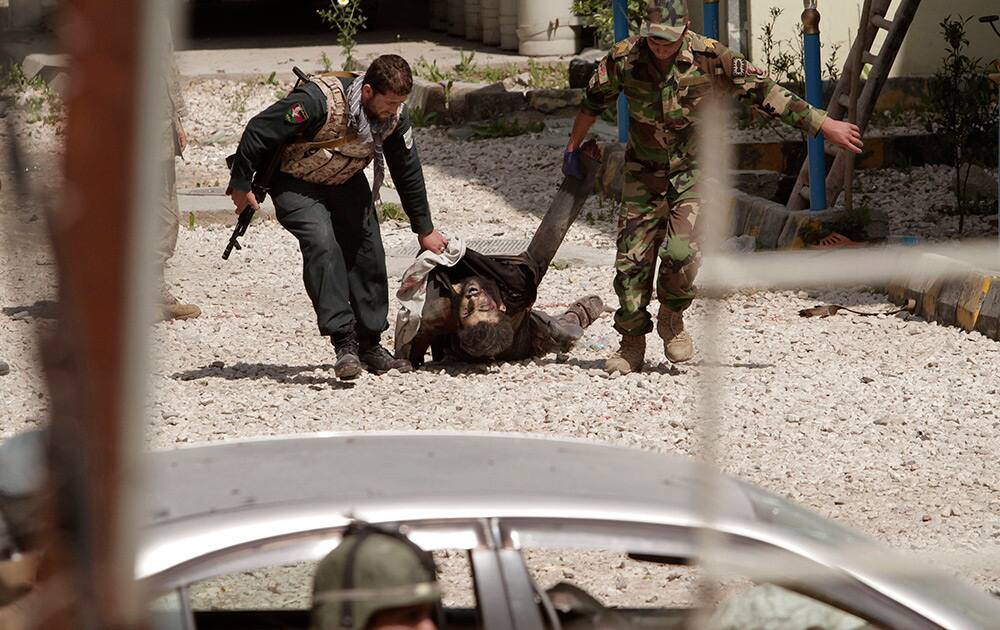 An Afghan Army solider and policeman drag the lifeless body of a suicide bomber from the scene after the Taliban staged a multi-pronged attack on a police station in Jalalabad, eastern Afghanistan.