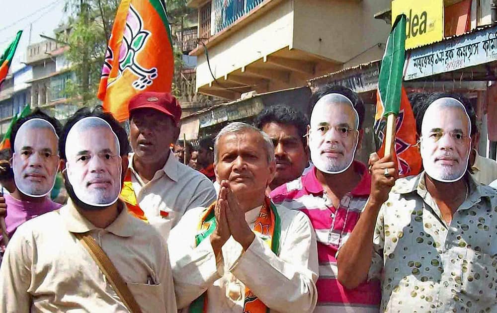 BJP candidate for Bolpur constituency Kamini Mohan Sarkar with supporters wearing mask of Narendra Modi during an election campaign road show in Birbhum district of West Bengal.