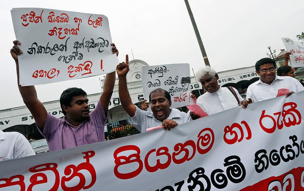 A Sri Lankan human rights activist shouts slogans as others hold a banner and placards against the weekend arrests of right activists in Colombo, Sri Lanka.