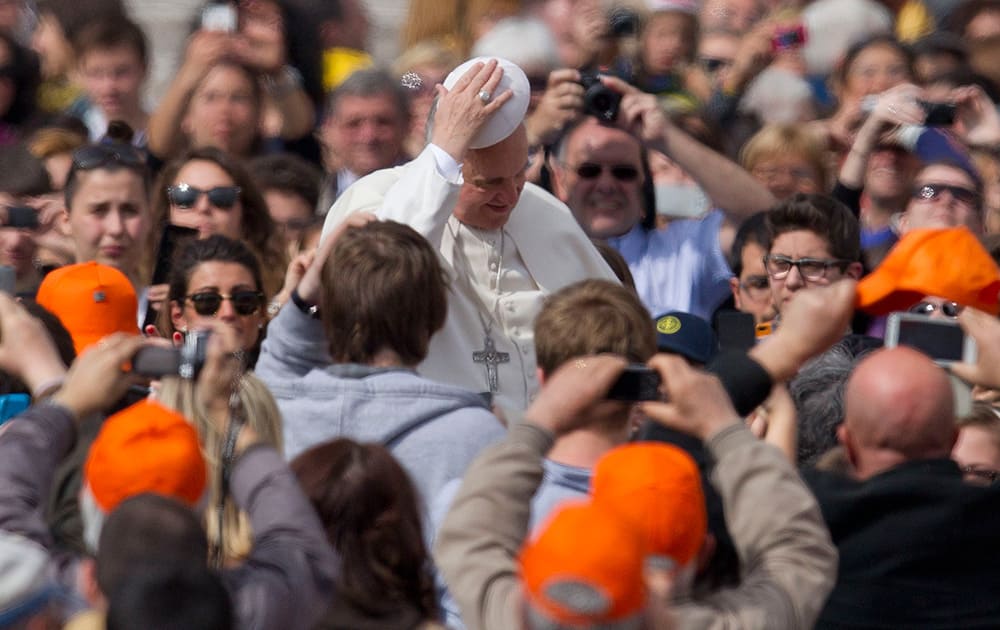Pope Francis wears a cap he was offered as he arrives in St. Peter`s Square at the Vatican for his weekly general audience.