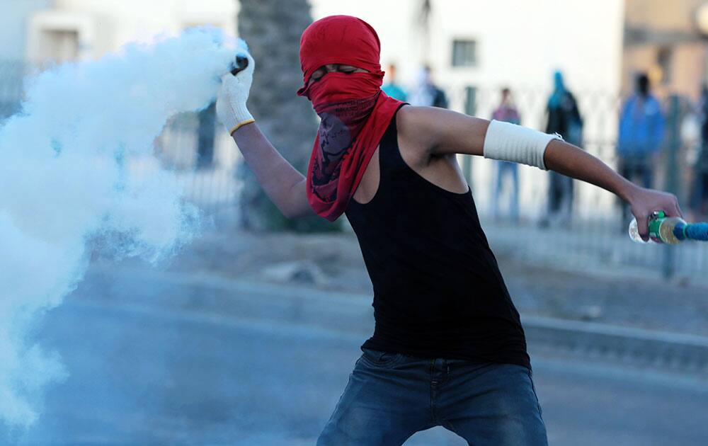 A Bahraini anti-government protester throws back a teargas canister toward riot police as Bahraini anti-government protesters clash with riot police firing teargas after a politically charged funeral procession for Jawad al Haawi, 49, in Sitra, Bahrai.