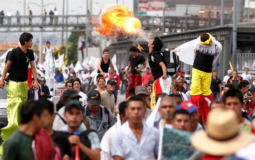 Colombian farmers are joined by acrobats while they march to demand that the government comply with the agreements reached last September for better prices for their products, in Bogota, Colombia.