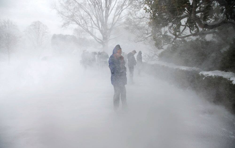 Journalists shield themselves from snow as Marine One helicopter carrying President Barack Obama arrives on the South Lawn of the White House in Washington, after visiting wounded service members at Walter Reed National Military Medical Center.