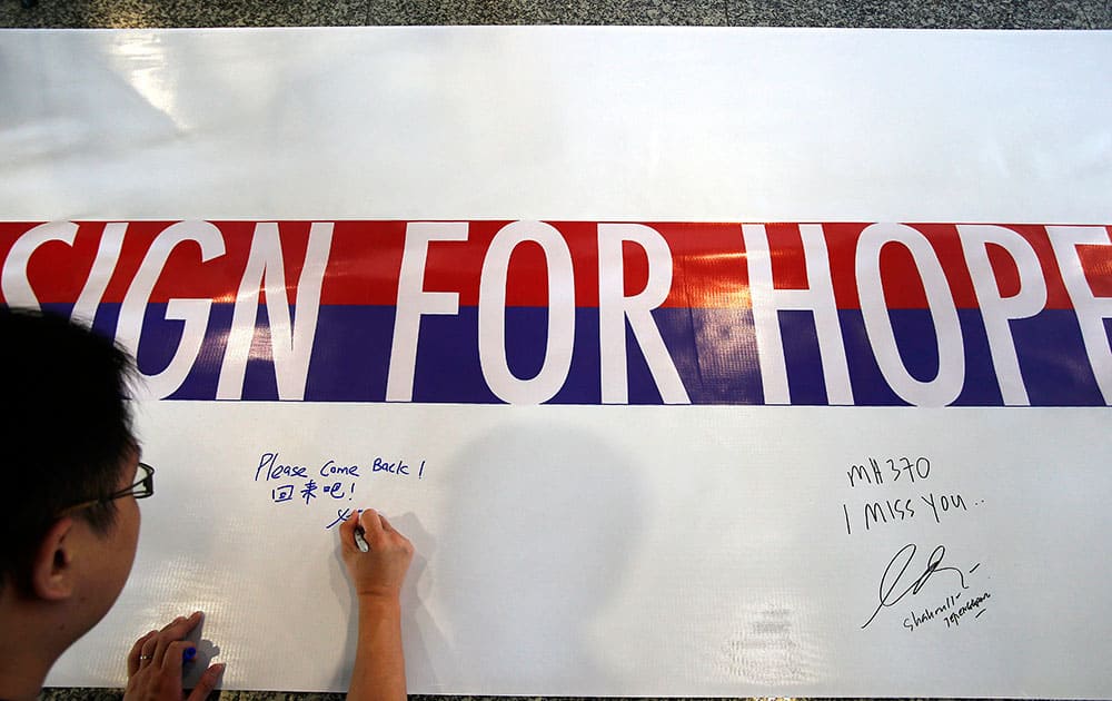 A man writes a message on a 60-meter long banner filled with signatures and well wishes for all involved with the missing Malaysia Airlines jetliner MH370 at the Kuala Lumpur International Airport.