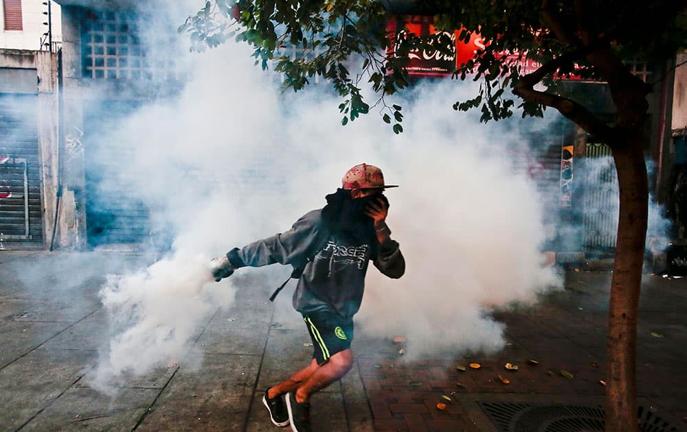 A masked protester throws back a tear gas canister fired by Bolivarian National Police during clashes in Caracas, Venezuela. Daily street protests and demonstrations continue in the capital and other cities.